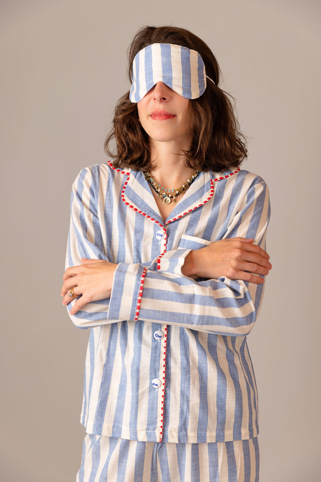 Woman wearing a blue and white striped pajama set with a matching eye mask.