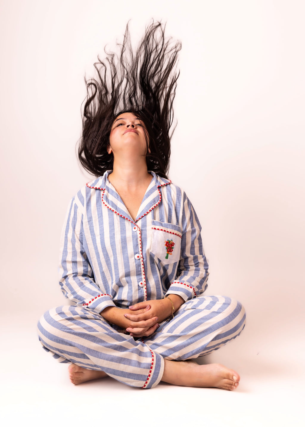 Person wearing blue and white striped pajamas with long hair being blown back against a plain background