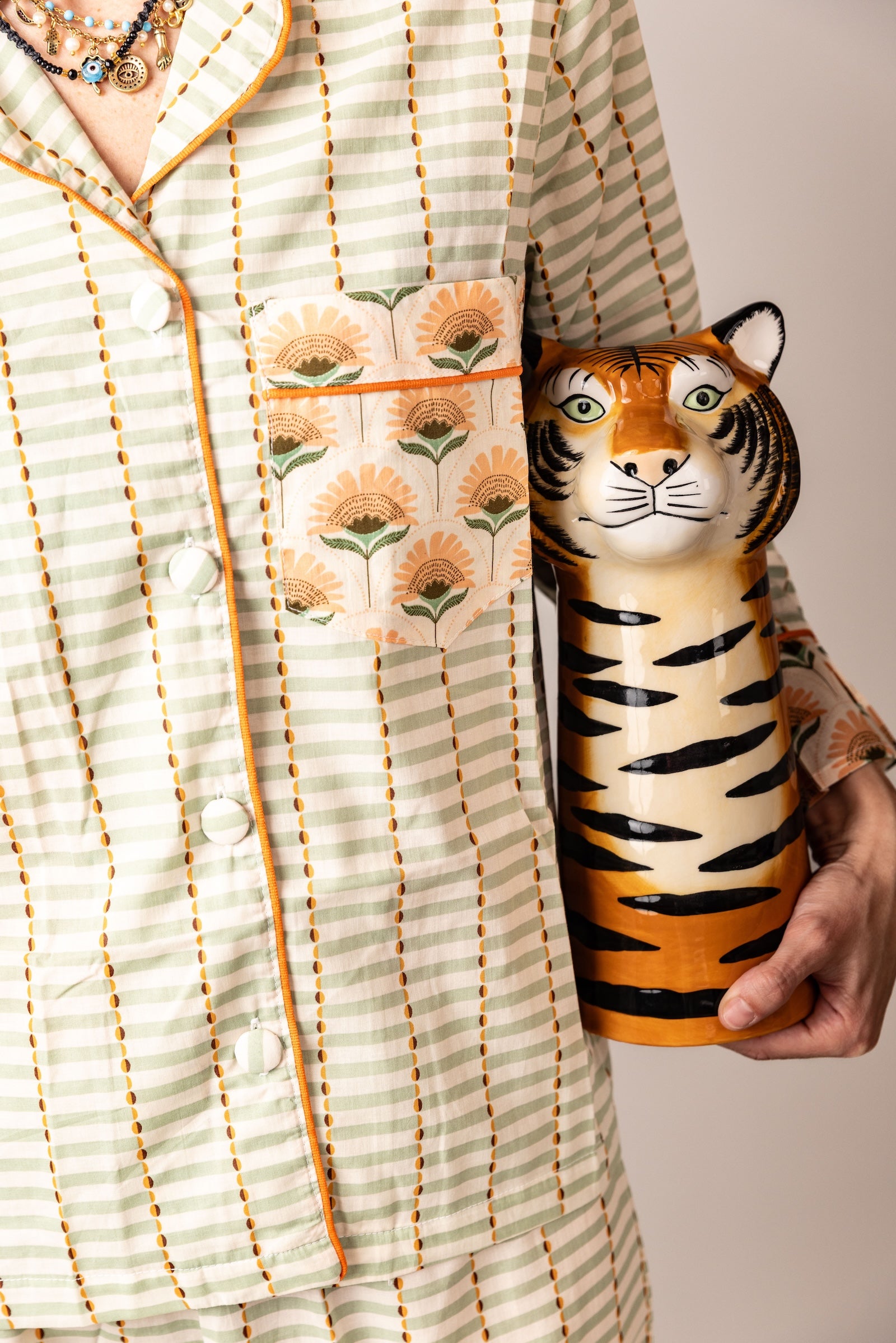 Person holding a tiger-shaped container with a floral-patterned garment in the background