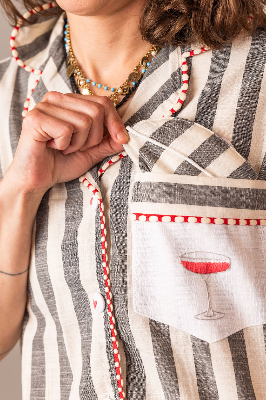 Person wearing a striped garment with a pocket featuring a COSMOPOLITAN glass design.