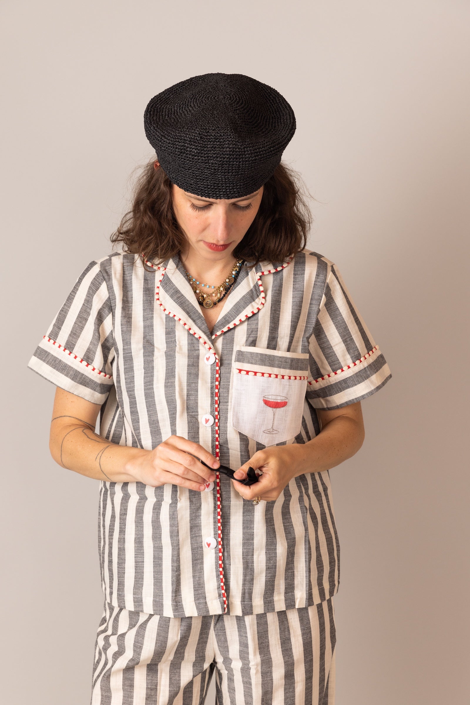 Woman wearing a striped PS61 pajama set with a black cap against a plain background